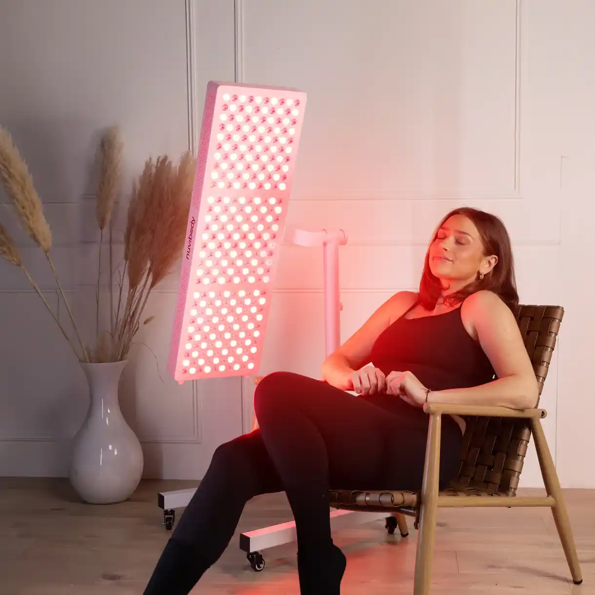 Vrouw die red light therapy gebruikt met een professioneel rood licht therapie paneel